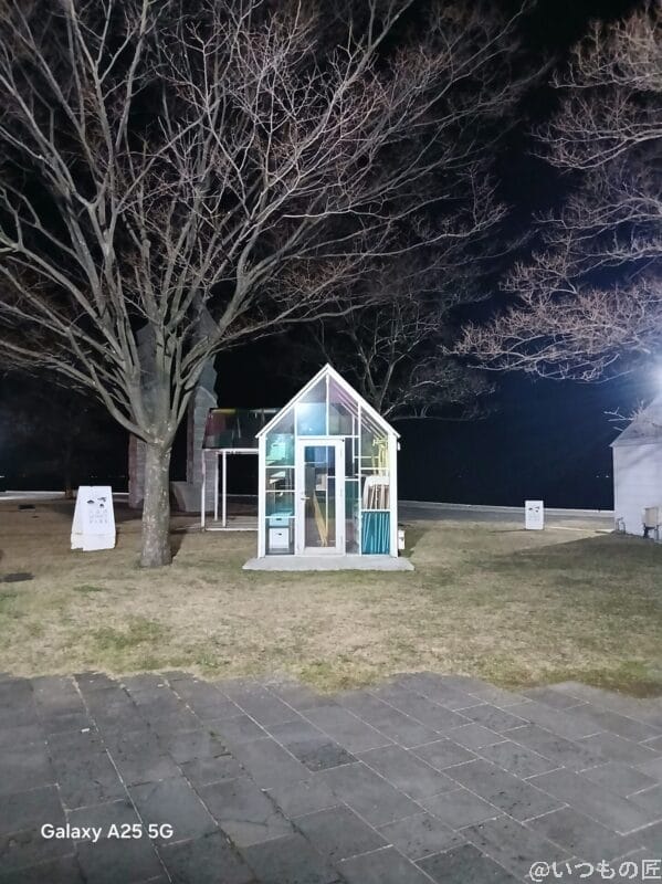 暗所でガラス張りの小屋を撮影した写真 | モバイル比較レビュー.jp Galaxy A25 5G カメラ 暗所でガラス張りの小屋を撮影した写真