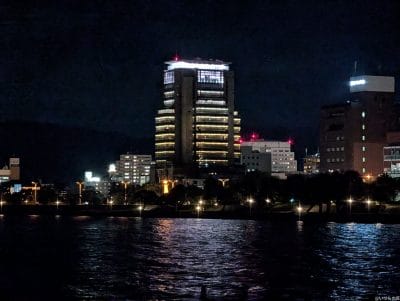 夜の海辺から見えるビル街 | モバイル比較レビュー.jp OPPO Reno14 5G カメラ 夜の海辺から見えるビル街